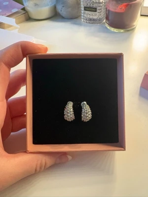 Silver örhängen - Snygga små silverörhängen dekorerade med vita pärlor runt hela ringen. Örhängena har en klassisk halvcirkelform. Perfekta för att ge en elegant touch till din outfit.