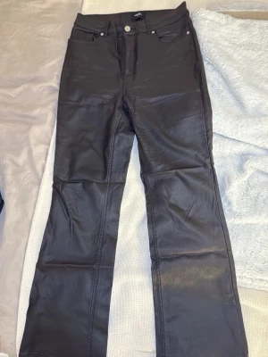 Svarta coated jeans från Vero Moda - Säljer ett par svarta coated jeans från Vero Moda med kick flare-modell. Materialet ger en snygg skinnlook som passar till många olika stilar. Passar till Petite i längd.