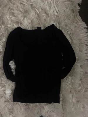 Svart långärmad tröja Gina Tricot - En svart långärmad tröja från Gina Tricot. Tröjan har en enkel och stilren design med rund halsringning och smal passform. Perfekt att matcha med jeans eller kjol för en clean look.