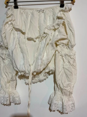 Vit spets tröja från Bisou's Project - Off Shoulder Blus med Spetsdetaljer från Bisou's Project  Säljer denna underbara off shoulder-blus från det charmiga franska märket Bisou's Project! En riktig boutique-pärla som utstrålar romantik och bohemisk elegans.  Storlek: S/m men mer åt S hållet.