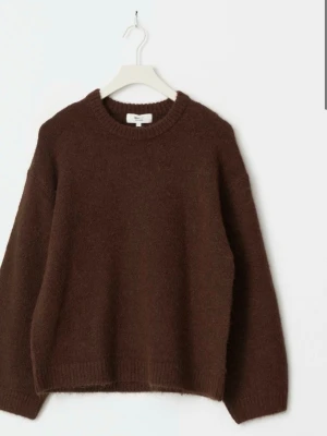 Brun stickad tröja från Arket - Mysig brun stickad tröja från Gina med rund halsringning och avslappnad passform. Tröjan har långa ärmar och ribbstickade muddar vid ärmslut och nederkant. Perfekt för lager-på-lager och höstiga outfits.