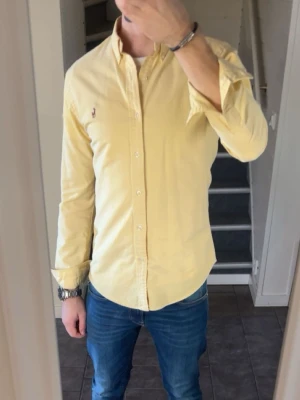 Skjorta Polo Ralph Lauren - Klassisk gul skjorta från Polo Ralph Lauren med button-down krage och broderad logga på bröstet. Skjortan har lång ärm, vita knappar och en normal passform. Perfekt till jeans eller chinos för en clean och stilren look. Skjortan har två fläckar se bild 5. 