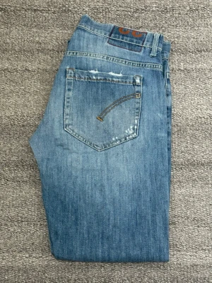 Blå George Dondup jeans - Snygga blå jeans med raka ben och lätt slitna detaljer på bakfickorna. Klassisk femficksmodell med kontrastsömmar och patch bak i midjan. Tillverkade i mjukt denimtyg som ger en avslappnad look. Mycket bra skick på dessa. Inga defekter och självklart äkta!