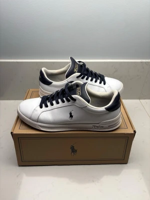 Vita Polo Ralph Lauren sneakers - Kom gärna med prisförslag! Snygga vita sneakers från Polo Ralph Lauren med mörkblå detaljer och logga på sidan. Skorna har mörkblå snören, låg profil och är tillverkade i slätt läder. Klassisk och stilren design som passar till det mesta. Org pris 1800kr+!