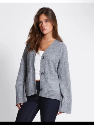 Grå kofta med knappar - Mysig grå kofta med v-ringning och stora knappar framtill. Koftan har två fickor och breda ribbade muddar vid ärmslut och nederkant. Perfekt att slänga på sig över en t-shirt för en chill look. Använd en gång.