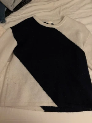 Stickad tröja med svartvit diagonal - Säljer en stickad tröja med coolt diagonalt mönster i svart och vitt. Tröjan har rund halsringning och långa ärmar. Materialet känns mjukt och mysigt, perfekt för kyligare dagar. Enkel men ändå unik design som sticker ut. 