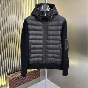 Svart Moncler cardigan jacka med huva - Svart cardigan jacka från Moncler med stickade ärmar och quiltad front. Jackan har huva med snörning, dragkedja framtill och en ficka med dragkedja på ärmen. Moncler-logga på vänster ärm. Perfekt för dig som vill ha en clean och modern look. Säljer min Moncler cardigan jacka eftersom jag redan har en vanlig och känner att det är onödigt att ha två av samma modell, den är i väldigt bra skick då den är använd max 3 gånger. Skriv om du har några frågor
