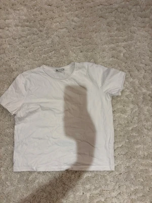 Vit basic t-shirt från Zara - En klassisk vit t-shirt från Zara i mjuk bomull. Modellen är kortärmad med rund halsringning och har en enkel, clean look som passar till allt. Perfekt att styla lager på lager eller bära som den är.