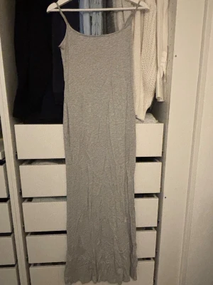 Grå långklänning från Gina Tricot - Oanvänd grå långklänning från Gina Tricot. Klänningen är ärmlös med smala axelband och har en rak, avslappnad passform. 