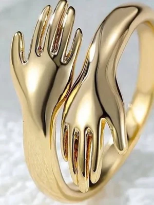 Guldfärgad ring med handmotiv - Unik guldfärgad ring i metall med två detaljerade händer som möts framtill. Ringen har en modern och konstnärlig design som verkligen sticker ut. Perfekt för dig som gillar statement-smycken och vill ha något annorlunda i din accessoarsamling. Vet dock inte vilket märke. Men den är justerbar så att den passar alla!