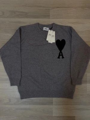 Grå stickad tröja från Ami Paris ~ S - Snygg grå stickad tröja från Ami Paris med svart hjärta och bokstaven A broderat på bröstet. Fraktar samma dag👌🏽