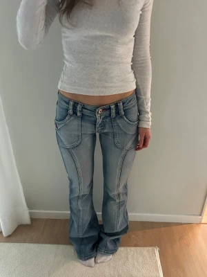 Ljusblå jeans  - Ljusblå lågmidjade jeans med unika detaljer. Storlek XS. Midja: 37x2 cm innerben: 85 cm 