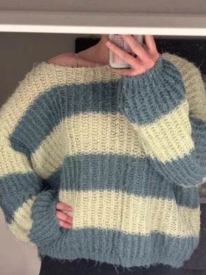 Randig stickad tröja från Vero Moda - Mysig stickad tröja från Vero Moda med breda ränder i ljusgul och blågrön. Tröjan har en oversized passform, grovstickad struktur och långa ärmar. 