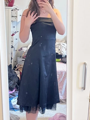 Black Y2K evening dress - Säljer en svart långklänning med rak urringning och lätt utsvängd kjol. Klänningen har ett tunt lager tyll längst ner som ger en extra detalj. Perfekt för dig som gillar en stilren och elegant look.