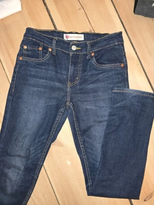 Mörkblå Levi's slim jeans - Snygga mörkblå slim fit jeans från Levi's med klassiska fem fickor och kontrastsömmar. Jeansen har en tidlös tvätt och är tillverkade i mjukt denimtyg. Perfekta för dig som gillar en smalare passform och vill ha ett par jeans som alltid funkar.