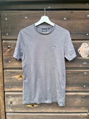 Grå t-shirt från Lyle & Scott  - Snygg grå t-shirt från Lyle & Scott med liten broderad logga på bröstet. Klassisk rund halsringning och korta ärmar. Tillverkad i mjuk bomull för en skön känsla och enkel stil.