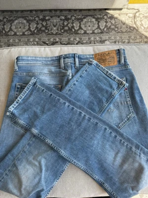 Ljusblå jeans från Replay - Säljer ett par ljusblå jeans från Replay med klassisk femficksmodell och snygg passform. Jeansen har en snygg tvättad look, bälteshällor och Replay-lapp bak i midjan. Perfekta för en avslappnad stil och passar till det mesta.