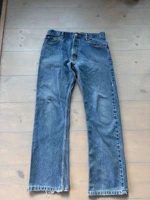 VINTAGE Levi's 517 Bootcut jeans blå - Klassiska blå Levi's 517 bootcut jeans med fem fickor och orange sömmar. Jeansen har en rak passform med lätt utsvängda ben och är tillverkade i slitstark denim. Perfekta för dig som gillar vintage och tidlös stil.