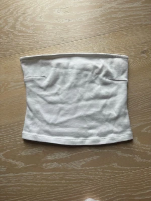 Vit tubtopp från Gina Tricot - Säljer en enkel och stilren vit tubtopp från Gina Tricot. Toppen är axelbandslös och har en rak passform, perfekt att matcha med jeans eller kjol. Tillverkad i mjuk bomull för en bekväm känsla hela dagen. Använt 1-2 gånger