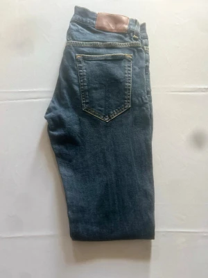 Tiger of sweden jeans - Tiger of Sweden jeans i mörkblå tvätt, storlek W31/L32. Slim fit med modern, smal passform och snygg slitning över lår och knän. Klassisk femficksmodell med låg midja.