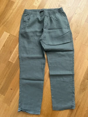 Grå linnebyxor från H&M Regular Fit - Snygga grå linnebyxor från H&M i modellen Regular Fit. Byxorna har resår i midjan med dragsko och sidofickor. Tillverkade i ett lätt och luftigt linnematerial som passar perfekt till sommaren. Enkel och avslappnad stil.