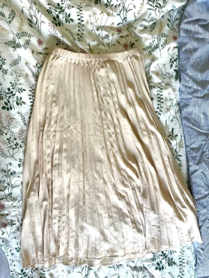 Beige långkjol  - En långkjol i ljus beige från Gina Tricot. Kjolen har ett elastiskt midjeband. (Finns ett par mindre röda fläckar på kjolen som visas i bland bilderna)
