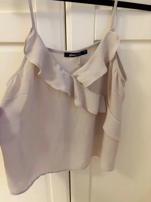 Linne med volanger - Lotte med volanger i beige/grå från Gina Tricot 