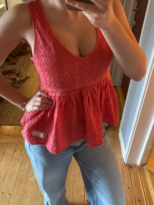 Korallfärgad topp - Jättesöt volang-topp med spetsdetaljer!! I jättebra skick och i en jätte trendig färg (visar sig bäst på bild 1&2)😍😍 den är i jättebra kvalitet och från Odd Molly. På sidan har den en dragkedja med en fin berlock på!! Skulle säga att storleken är XS/S