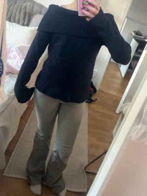 Mörkblå off shoulder stickad tröja - Mysig mörkblå stickad tröja med bred off shoulder-krage och långa ärmar. Tröjan har en avslappnad passform och ribbstickade muddar vid ärmslut och nederkant. Perfekt för dig som gillar en trendig och bekväm stil.