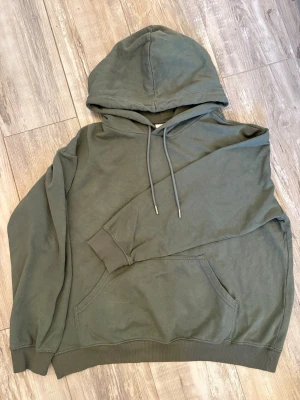 Grön hoodie med magficka - En grön hoodie med klassisk huva, dragsnören, och en magficka framtill. Enkel att matcha med jeans eller joggers, perfekt för en avslappnad look! Pris går alltid att diskutera💕