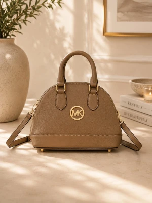 Beige handväska från Michael Kors - Snygg beige handväska från Michael Kors i skinn med guldfärgade metalldetaljer och logotyp framtill. Väskan har både handtag och avtagbar axelrem, samt rundad form och struktur i materialet. Perfekt för dig som vill ha en stilren och trendig accessoar.
