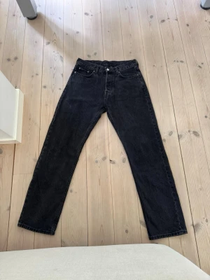 Svarta raka jeans - Säljer ett par svarta jeans med rak passform och klassisk femficksdesign. Jeansen har hög midja och är tillverkade i ett kraftigt denimtyg. Perfekta för en avslappnad och stilren look.