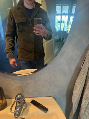 Mörkgrön overshirt i manchester Ralph lauren - Stilren mörkgrön overshirt i manchestertyg med klassisk krage och knäppning framtill. Två bröstfickor med lock och knappar ger en cool utility-vibe. Perfekt lager på lager-plagg för dig som gillar en avslappnad men trendig look. Skriv till mig om ni vill ha bilder på hur den sitter Med vänlig hälsning, Oliwer!