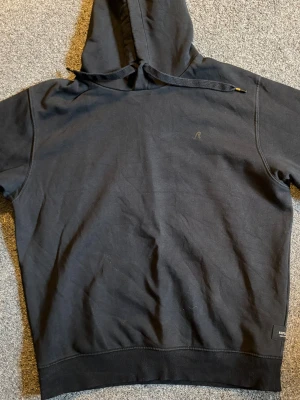 Svart hoodie från Replay - Säljer en svart hoodie från Replay med klassisk huva och dragsko. Diskret Replay-logga på bröstet och en liten etikett vid nederkanten. Hoodien har ribbade muddar och är tillverkad i mjukt bomullsmaterial. Perfekt för en avslappnad och stilren look!