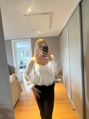 Vit blus med prickar från Boohoo - Säljer en vit blus från Boohoo med transparenta långärmar och små prickar i tyget. Blusen har en söt volang vid bröstet och en luftig passform med bred, fyrkantig halsringning. Perfekt för dig som gillar trendiga och romantiska detaljer.
