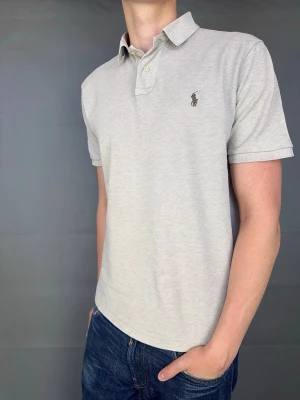 Ralph Lauren piké - Ralph Lauren piké  Märke: Polo Ralph Lauren Storlek: L Passform: Custom Slimfit Färg: Beige  Skick: Bra Beskrivning: har upprivningar längst ner på tröjan på båda sidor. Inget som syns så tydligt. Se bilder. Annars bra. Modellen på bilden: 183 cm / 75 kg