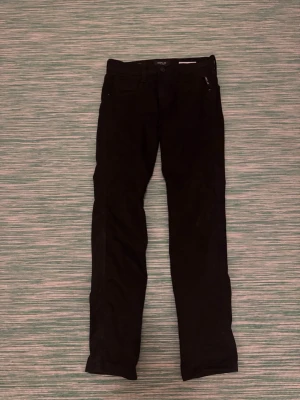 Svarta slim jeans från Replay - Säljer ett par svarta slim fit jeans från Replay, modell Anbass Hyperflex. Jeansen har klassisk femficksdesign, normalhög midja och stretchigt material för extra komfort. Perfekta för dig som gillar en stilren och modern look.passar dig i 175 i längd
