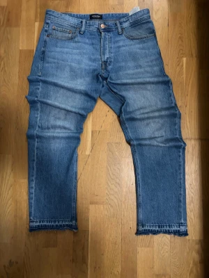 Blå raka jeans med rå kant - Blå jeans från Jack & Jones i superbra skick  Sitter riktigt snyggt och passar till allt. Använda få gånger så inga slitningar eller fläckar.  • Storlek: 33/32 • Färg: blå • Passform: Loose 