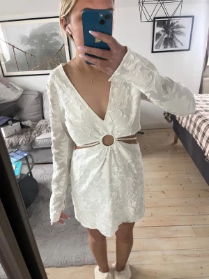 Sommarklänning  - Vit kort sommarklänning med öppning vid magen, finns snöre att knyta som man vill! Dragkedja i ryggen! Fläckar, därav priset! 