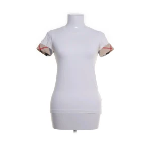 Vit Burberry t-shirt med rutiga detaljer - Snygg vit t-shirt från Burberry med klassiska rutiga detaljer på ärmsluten. T-shirten har en slim passform och korta ärmar. Perfekt för dig som vill ha en enkel men ändå lyxig look. Storlek xs