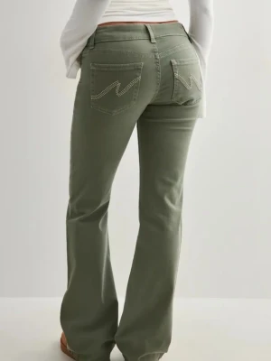Olivgröna bootcut jeans från Nelly - Snygga olivgröna bootcut jeans från Wrangler med klassiska fickor bak och kontrastsömmar. Jeansen har normal midja, utsvängda ben och dubbla knappar framtill. Perfekta för en avslappnad och trendig look.