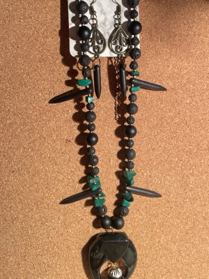 Handgjort halsband i återbrukade pärlor  - Handgjort halsband med återbrukade pärlor, lavastenar med mera. Halsbandet har en cool boho-vibe och mixar matta och blanka material. Matchande örhängen med metall och pärlor ingår. Örhängen är inte nickelfria.