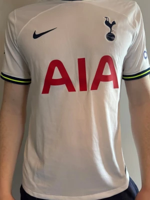 Tottenham Hotspur matchtröja Nike - Säljer en vit Tottenham Hotspur matchtröja från Nike med klubbmärke och sponsortryck på bröstet. Tröjan har Premier League-märke på ärmen och detaljer i mörkblått och gult vid ärmsluten. Tillverkad i lätt och ventilerande material, perfekt för fotboll eller träning. Nypris ca 1200. Köpt från unisport. 