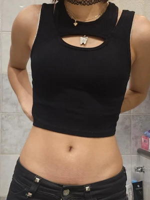 Svart ribbad croppad linnetopp - ❗️Skriv innan köp❗️Svart croppad linnetopp med ribbad struktur och unik cut-out detalj vid halsen. Toppen är ärmlös och har en tight passform som framhäver figuren. Har haft i flera år och ganska använd.
