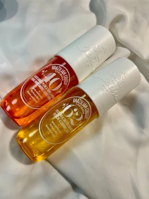 Sol de Janeiro Brazilian Crush duo - Två parfymsprayer från Sol de Janeiro: Cheirosa 40 med bärnsten och vanilj i rosa flaska, samt Cheirosa 62 med pistage och salt karamell i gul flaska. Båda har vita lock och trendig design, perfekta för dig som gillar söta och unika dofter. Gula är ungefär hälften av 90ml, Rosa är ungefär hela 90ml och är använd någon enstaka gång (bilder).