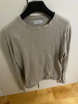 Beige tröja från Jack & Jones - En stilren beige tröja från Jack & Jones med rund halsringning och långa ärmar. Tröjan är tunnstickad och passar perfekt till lager-på-lager-stil. Enkel design utan tryck eller mönster, vilket gör den lätt att matcha med andra plagg. Storlek xs men passar som s. Bara att skriva om du har några frågor! 💪🏼