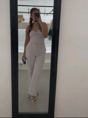 Vita  kostymbyxor med hög midja - Säljer ett par vita kostymbyxor med hög midja och raka ben. Byxorna har bälteshällor och en klassisk design som ger en snygg siluett. Perfekta för dig som vill ha en stilren och modern look. Använd 3 gånger vid fest tillfällen. Ordinarie pris från Gina tricot 400kr 