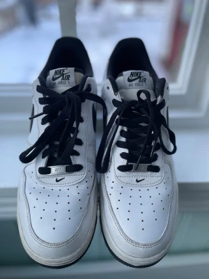 Nike Air Force 1 Vit/Svart Strl 46 (US 12) - Nike Air Force 1 i vit med svart detalj, storlek 46 / US 12. Klassisk och tidlös modell med skinnöverdel och bekväm passform. Clean condition med normala, lätta användningsspår. Ingen box. Se bilder för skick.