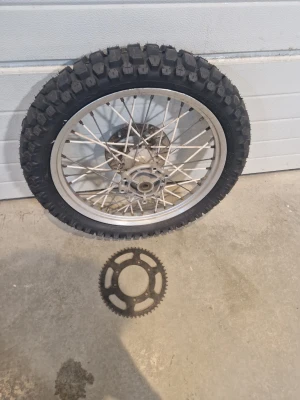 Drac fälgar - Säljer ett grovmönstrat motocrosshjul med ekrar och aluminiumfälg. Däcket är svart med kraftigt mönster för terrängkörning. Ett löst drev i metall ingår. Perfekt för dig som bygger eller reparerar cross.