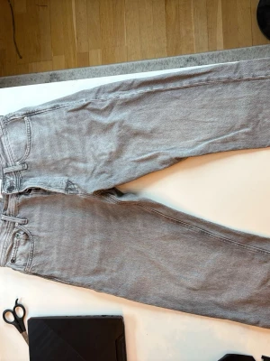 Grå raka jeans från Levi's - Säljer ett par klassiska grå jeans från Jack and jones med rak passform och fem fickor. Jeansen har en ljusgrå tvätt, bälteshällor och Levi's ikoniska läderpatch bak i midjan. Perfekta till vardags för en avslappnad look.